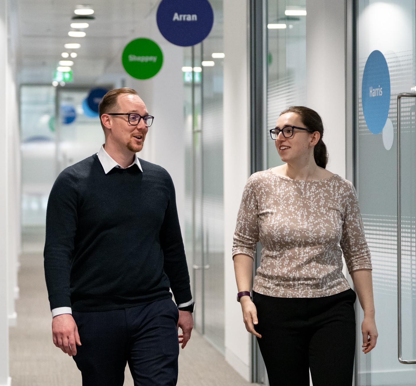 Man and woman chatting as they walk along a corridor