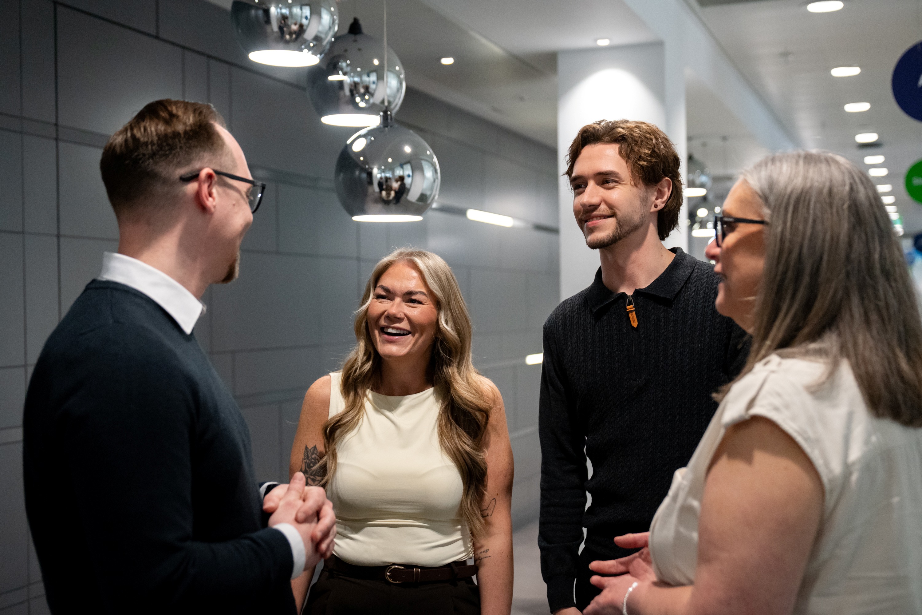 Two women and two men standing in a lobby talking and smiling.