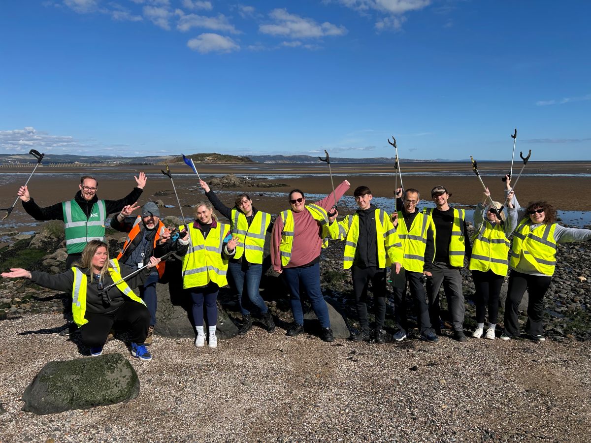 Large group of Business Stream colleagues celebrating litter pick on beach