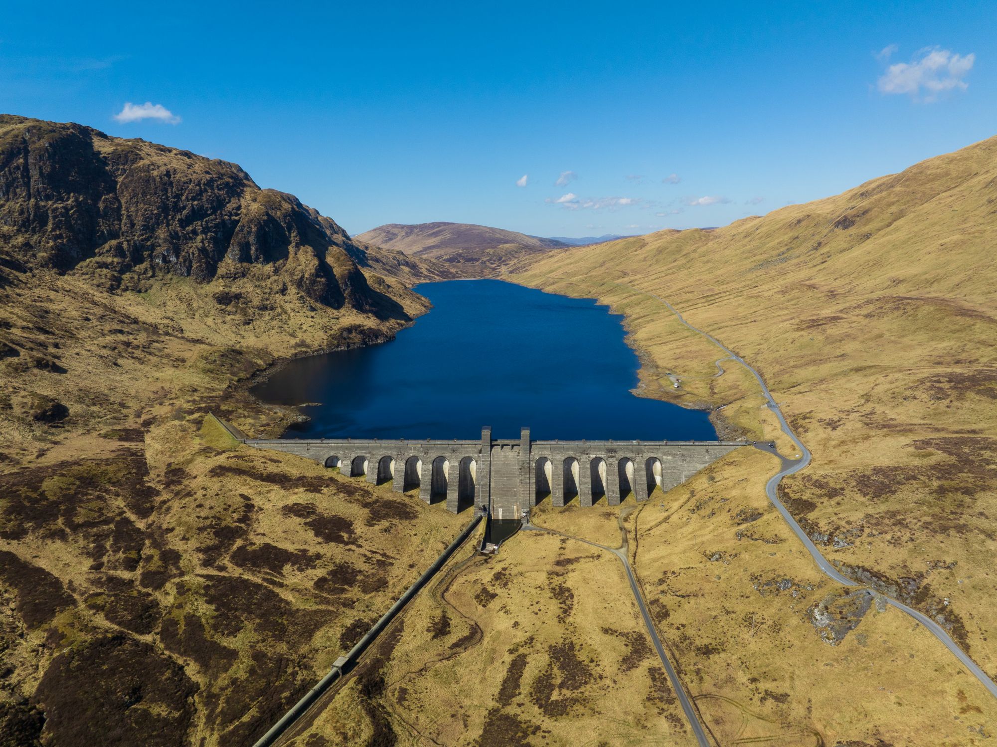 Lochan na Lairige viewed from high up with dam in foreground and blue sky above