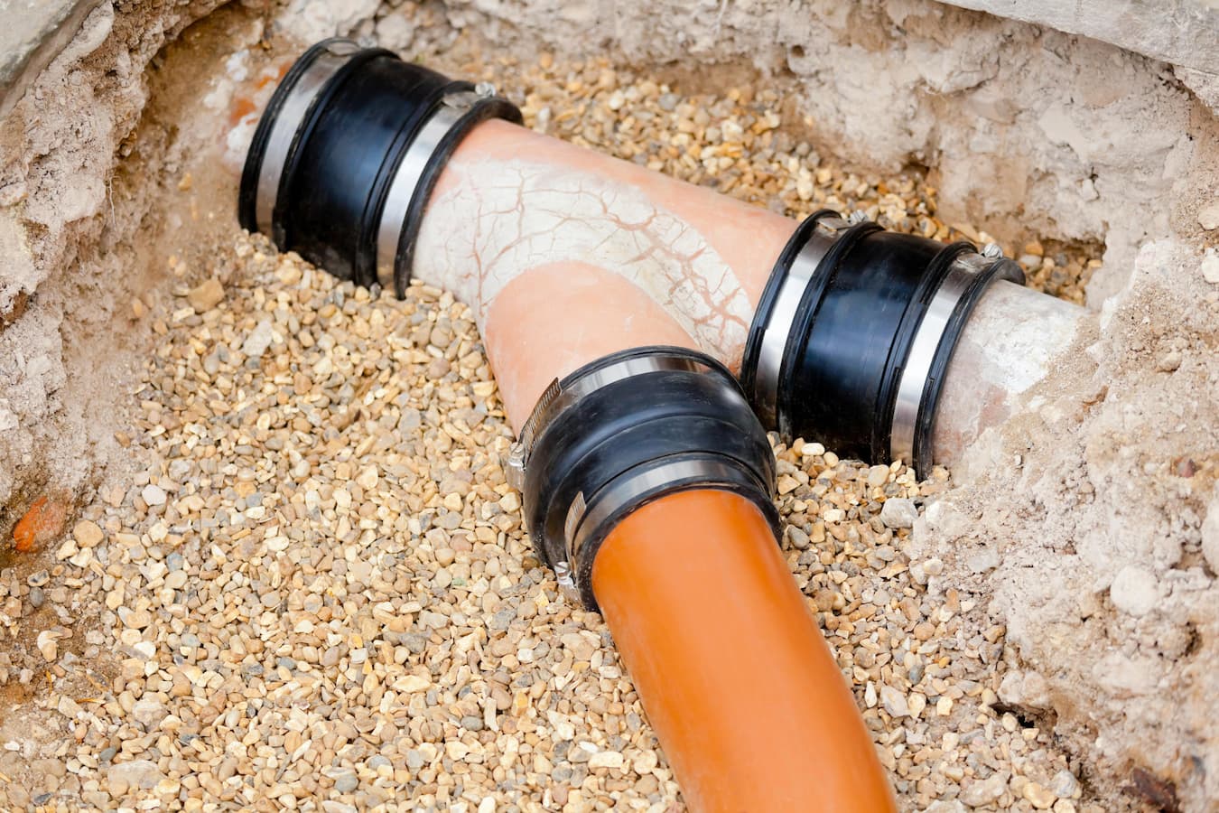 Junction of clay sewage pipe surrounded by gravel