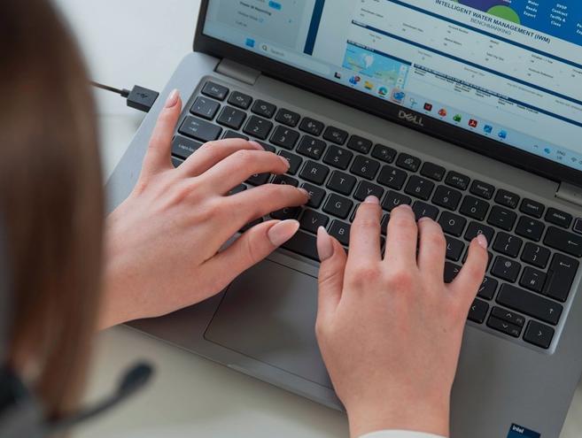 A woman's hands, typing on a laptop