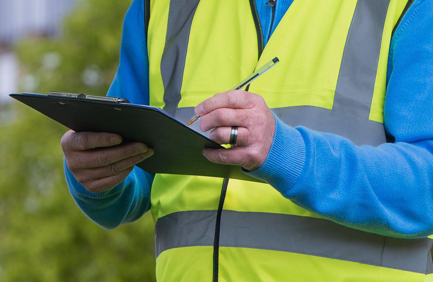 Man in hi-vis holding clipboard and pen