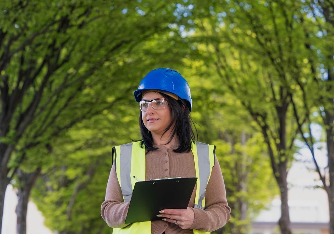 Construction worker, surveying project with trees in background