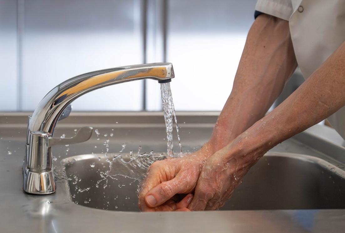 A man's hands under a running tap