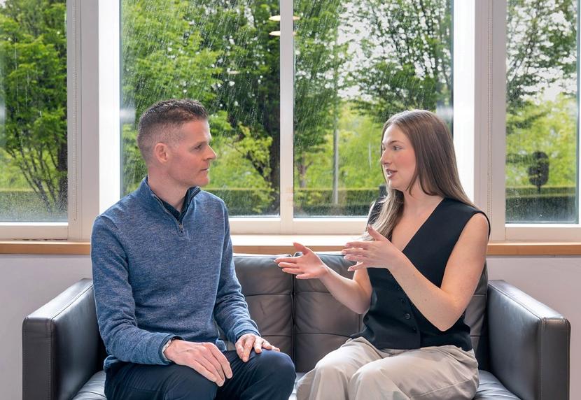 A woman explaining something to a man, while sitting on a sofa