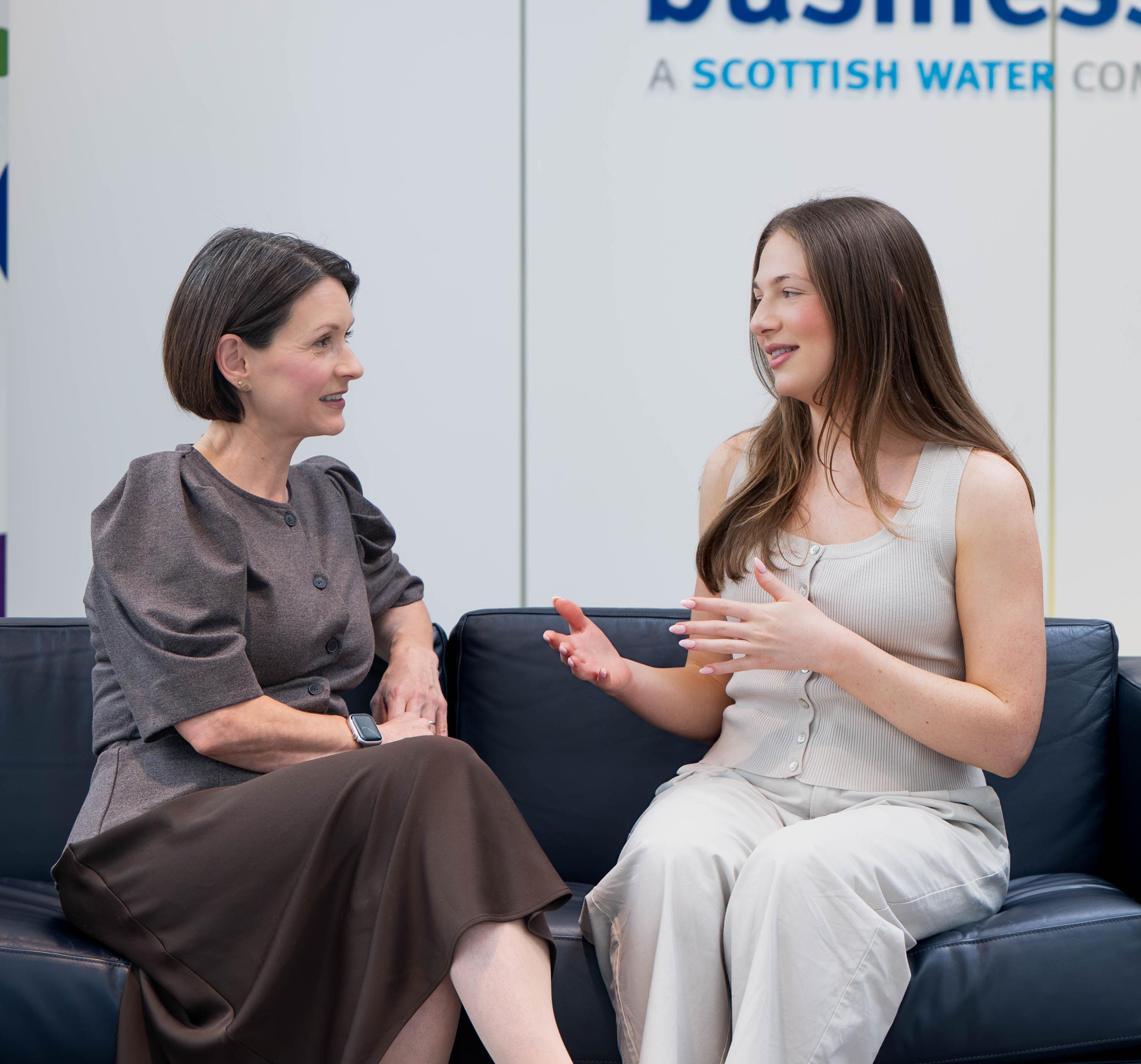 Two women sitting talking on a sofa in Business Stream reception
