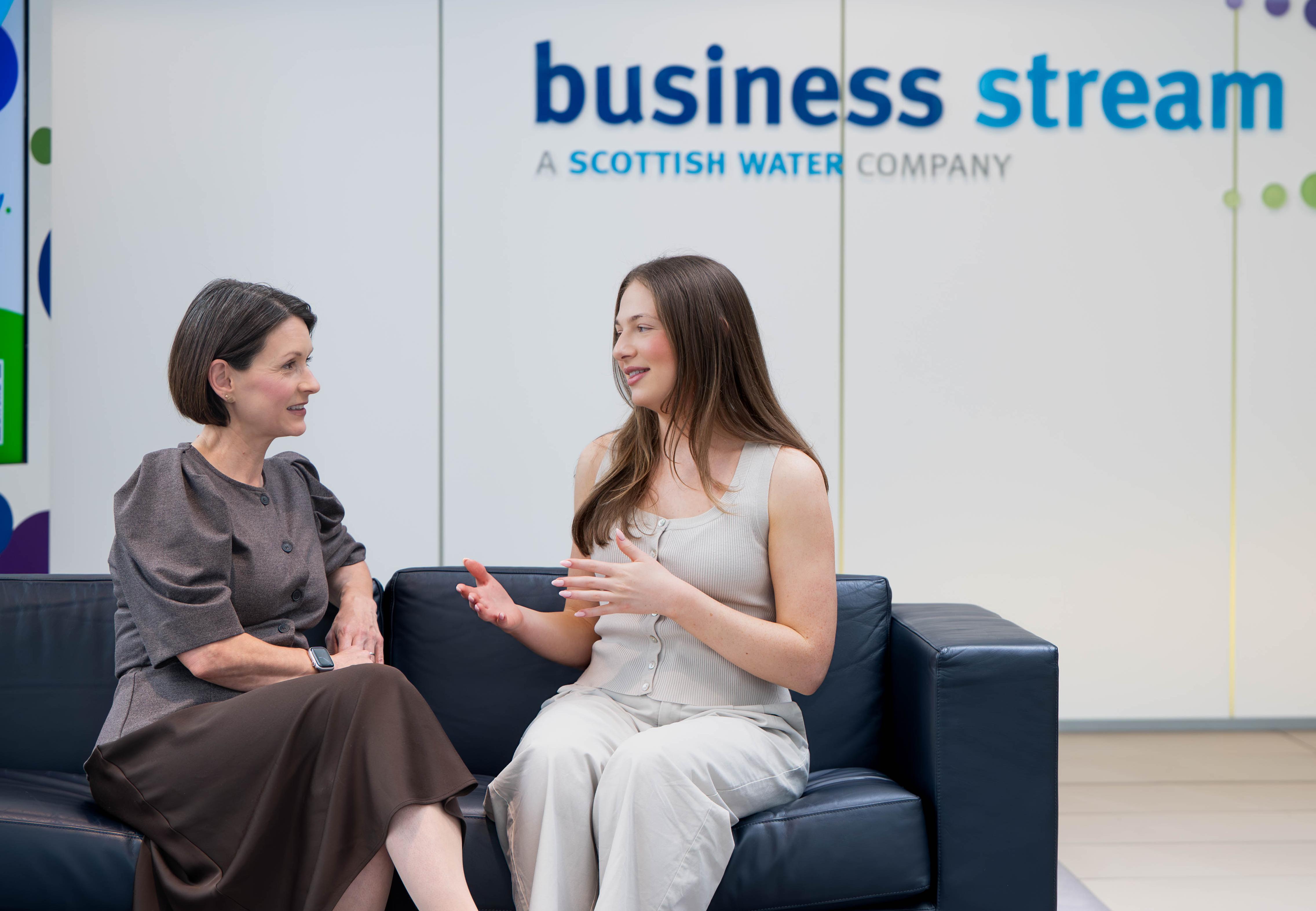 Two women sitting talking on a sofa in Business Stream reception