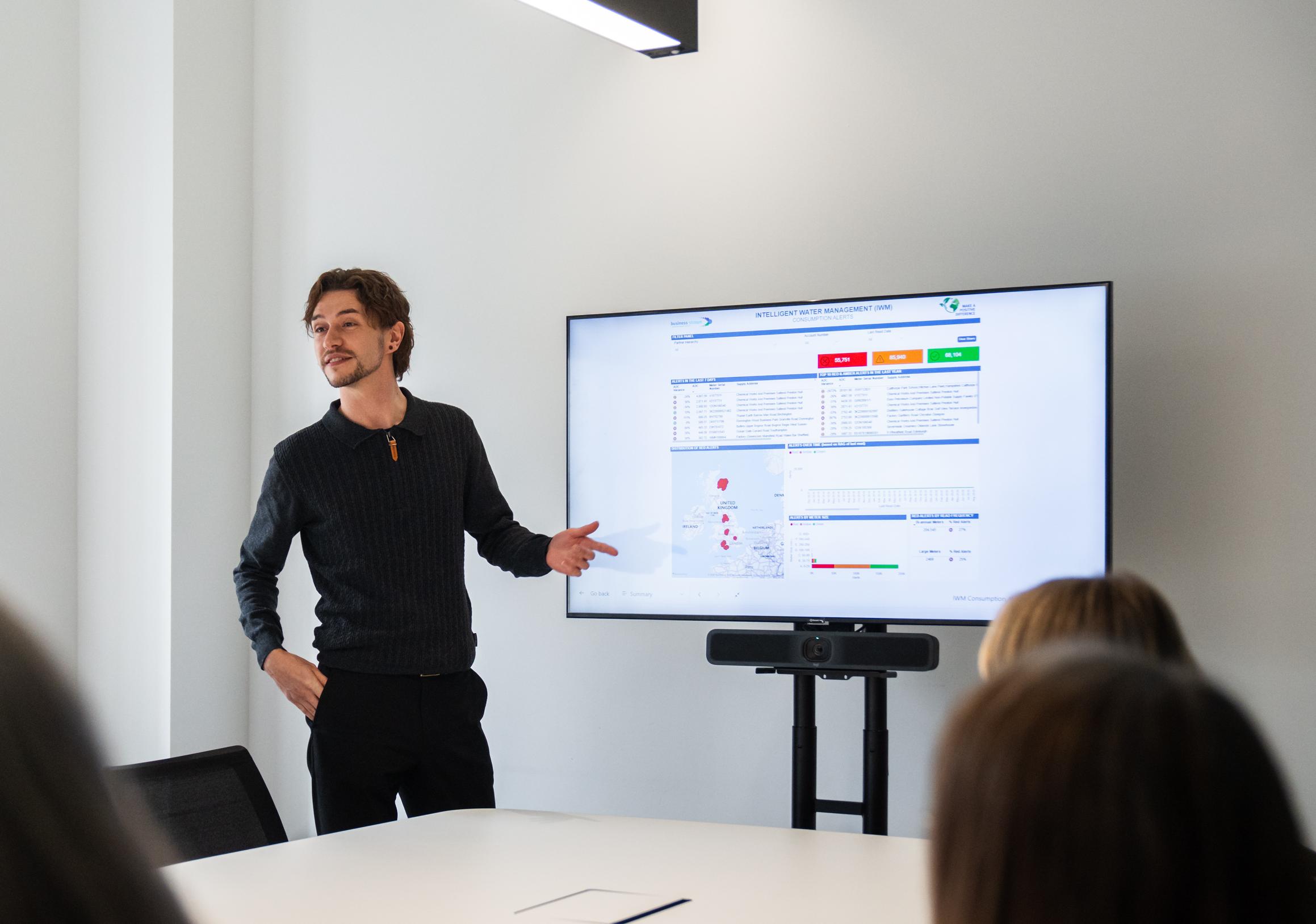 Man at large screen presenting data in a meeting room