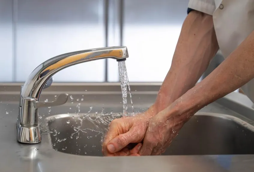 A man's hands under a running tap