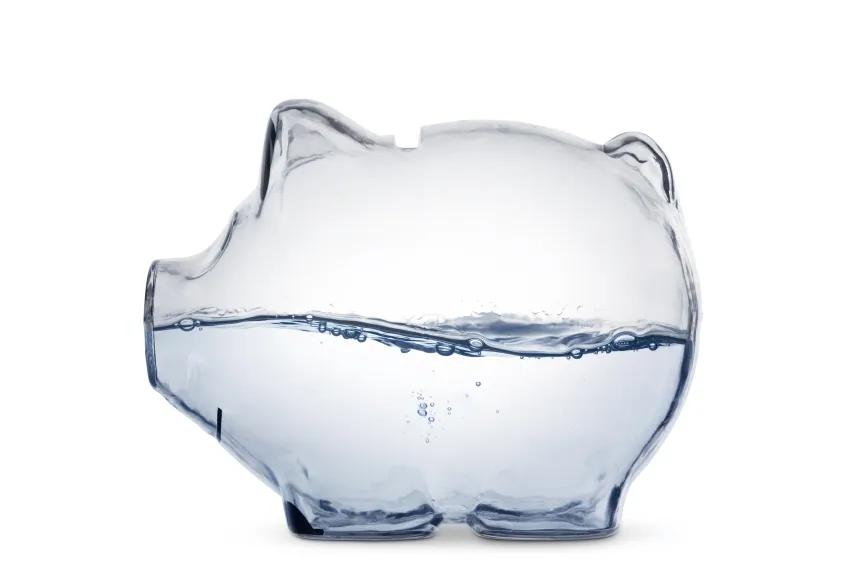 Transparent piggy bank half filled with water