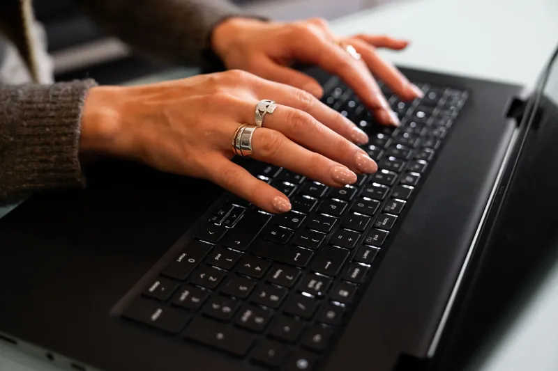 Close-up of woman's hands operating a laptop keyboard
