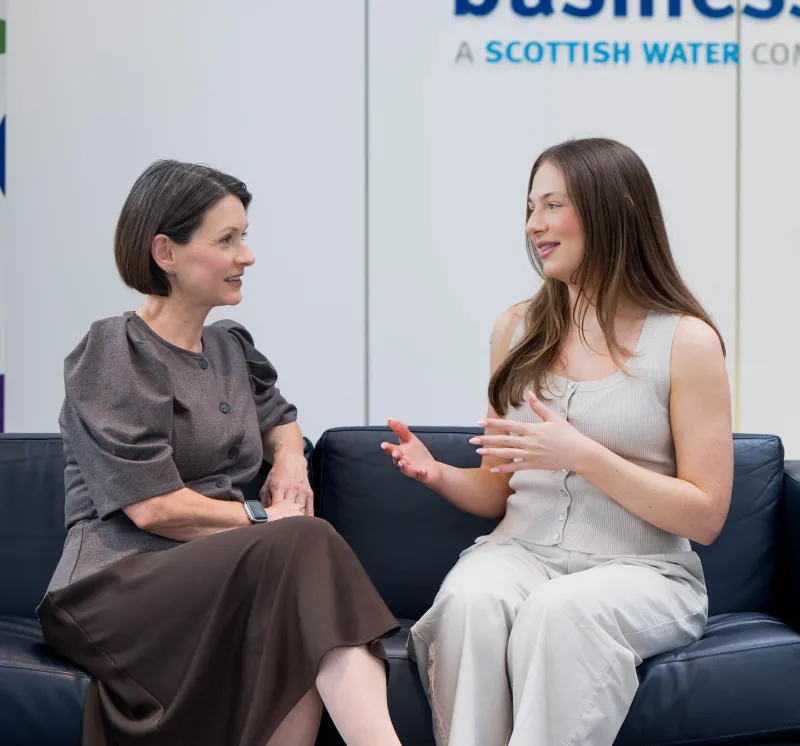Two women sitting talking on a sofa in Business Stream reception